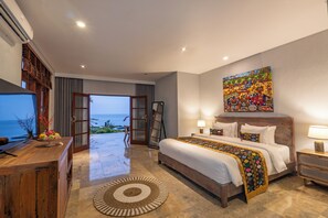 Ein geräumiges Schlafzimmer mit einem großen Bett, einem Holztisch, einem Fernseher und Blick aufs Meer.