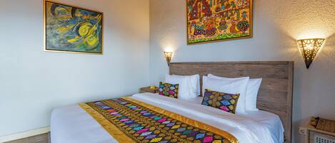 A hotel room with a large bed, a wooden headboard, and two wall-mounted lights.