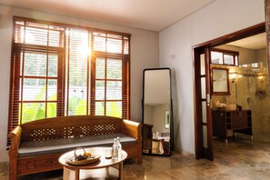 A room with a wooden bench, a round table with a teapot, a large mirror, and a bathroom visible through an open door. - Seaside Oceana Resort by Mahaprana (Kubutambahan)