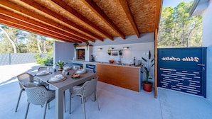 An outdoor kitchen area with a dining table set for four, surrounded by wicker chairs. - Villa Antea in Vela Luka (Vela Luka)