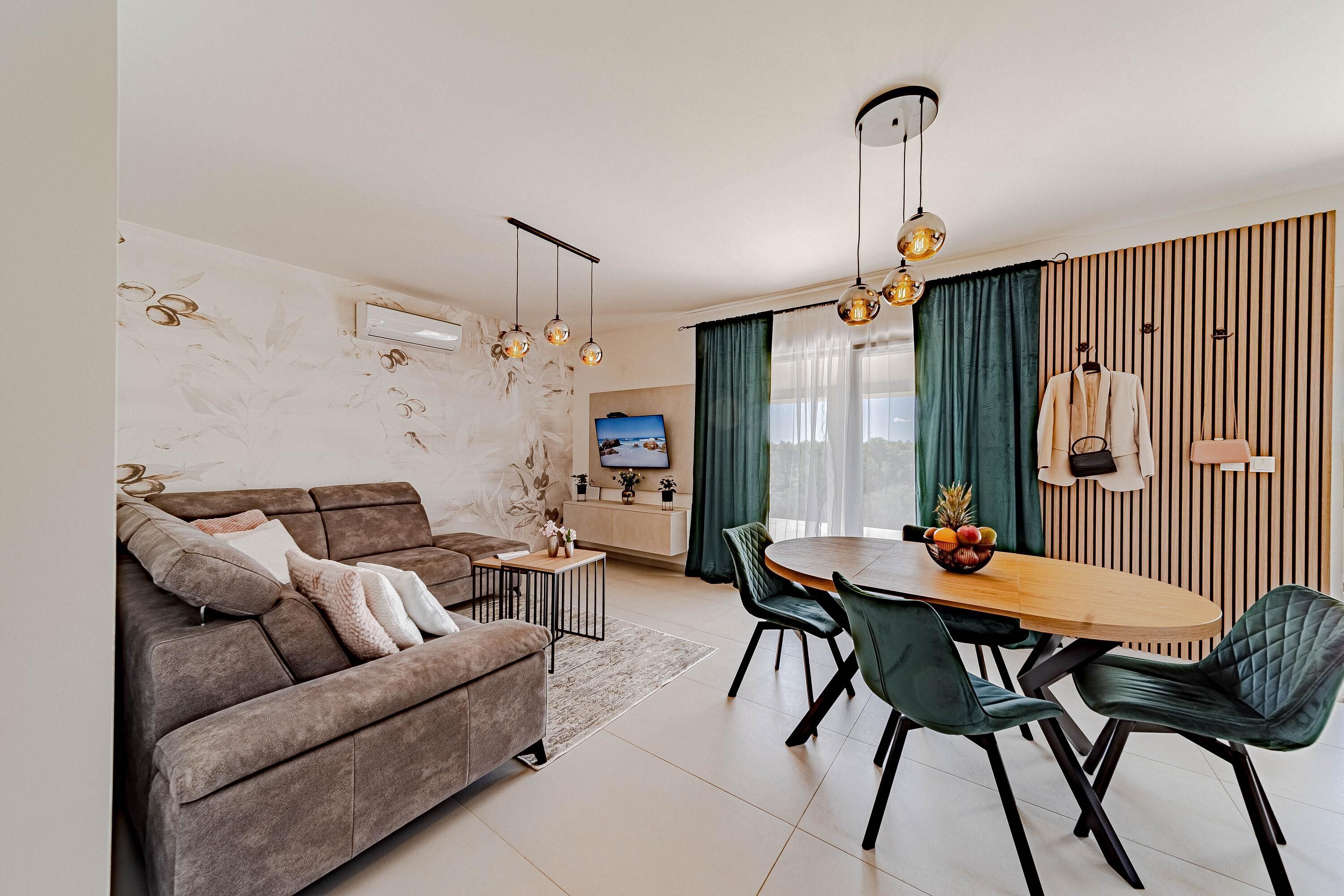 A modern living room with a sofa, dining table, chairs, and a TV.