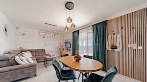 A modern living room with a brown sofa, a wooden dining table, and green upholstered chairs. - Villa Antea in Vela Luka (Vela Luka)