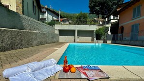 Una piscina con un asciugamano, una bottiglia e della frutta sul bordo.