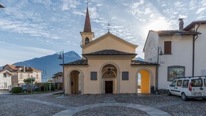 Una chiesa con un campanile, un pavimento in pietra circolare e una montagna sullo sfondo.
