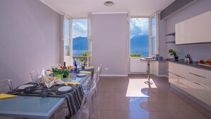 A modern kitchen with a dining area, large windows offering a view of the sea and mountains, and a well-lit space with ceiling lights. - Casa Daniele in Menaggio (Menaggio)