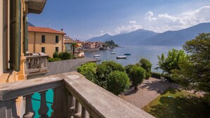 A coastal town with buildings along the waterfront, boats in the water, and mountains in the background. - Casa Daniele in Menaggio (Menaggio)