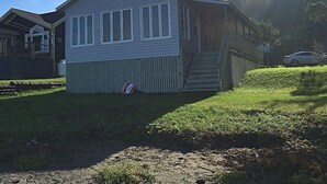 Ein zweistöckiges Haus mit einer Veranda, einem kleinen Vorgarten und einem Auto im Hintergrund.