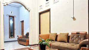A lobby with a brown leather sofa, a glass coffee table with a plant, and a wooden door. - JOGJA DAY INN (Yogyakarta)