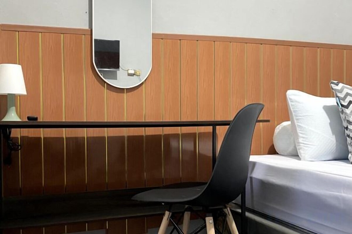 Une chambre d’hôtel avec un lit, une chaise, un bureau, une lampe et un miroir.