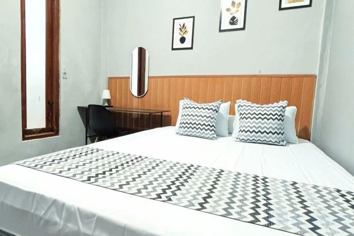 A hotel room with a bed, a desk, and a chair.