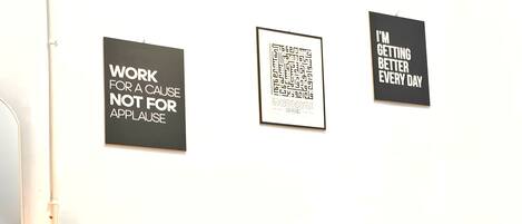 A hotel room with a bed, a nightstand, a lamp, and three motivational posters on the wall.