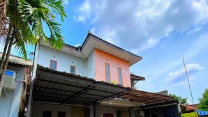A two-story house with a covered porch and a small garden area. - JOGJA DAY INN (Yogyakarta)