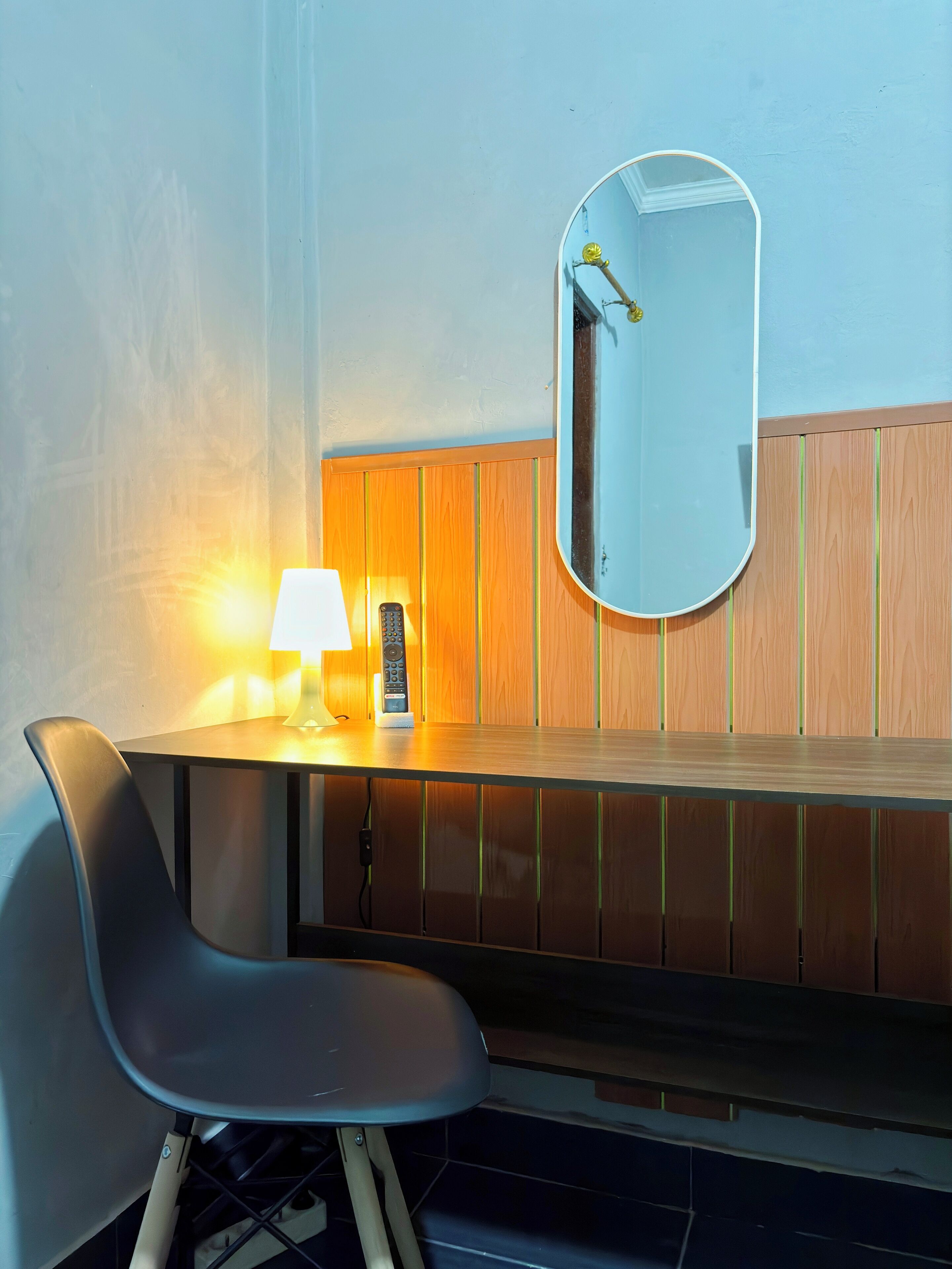 A modern bathroom with a wooden vanity, a mirror, a lamp, and a chair.