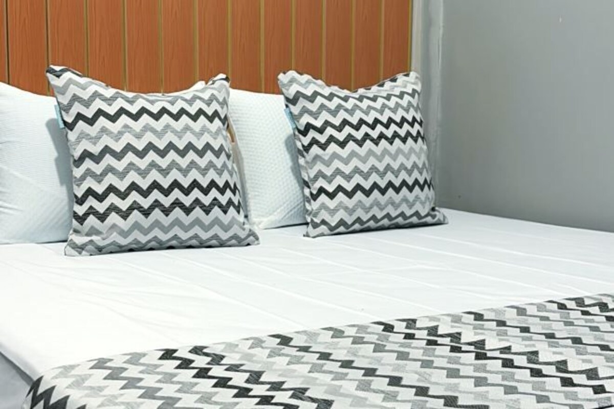 Una cama con dos almohadas y una colcha estampada.