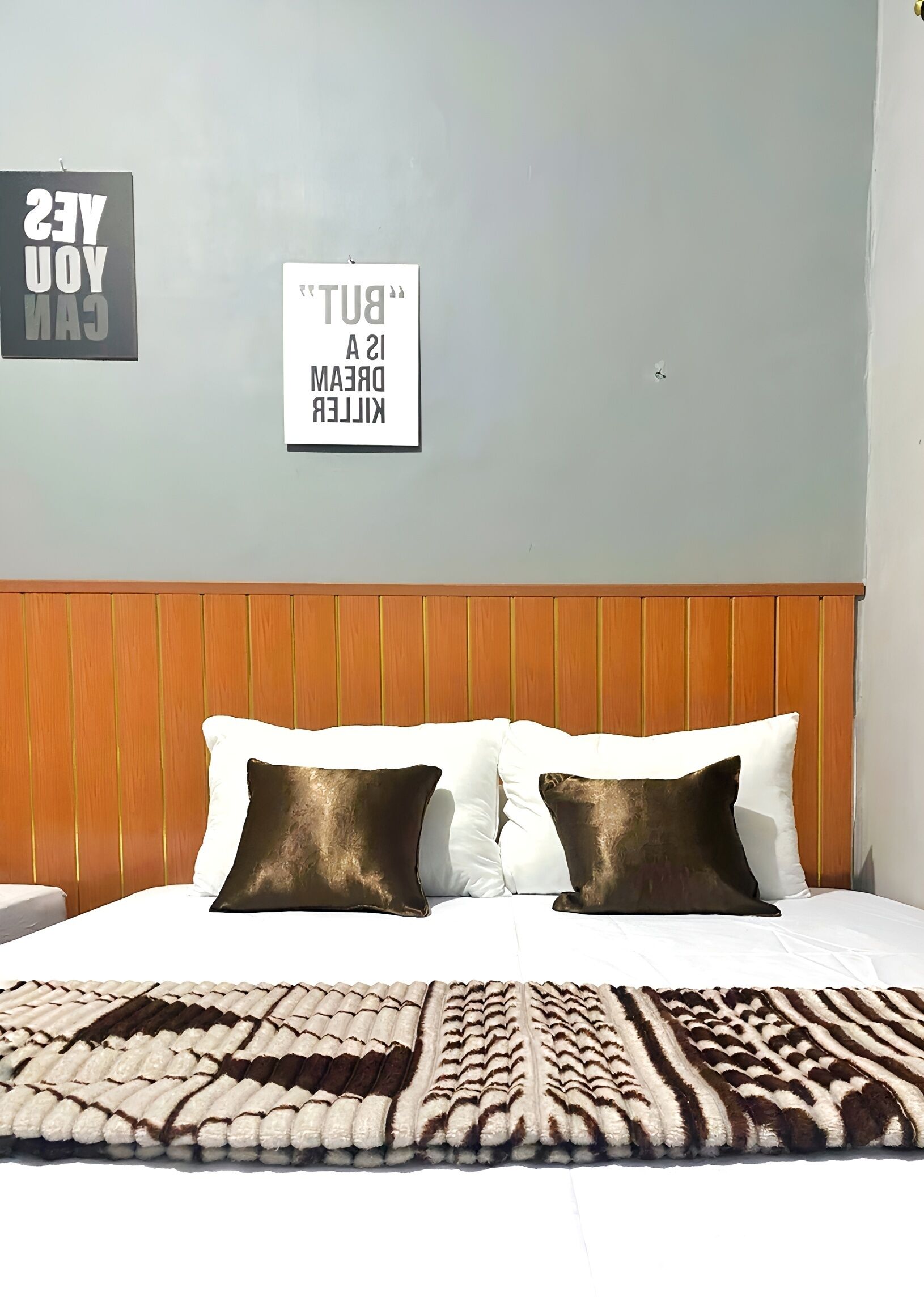 Una habitación de hotel con cabecera de madera, ropa de cama blanca y alfombra estampada.