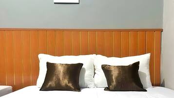 Una habitación de hotel con cabecera de madera, ropa de cama blanca y alfombra estampada.
