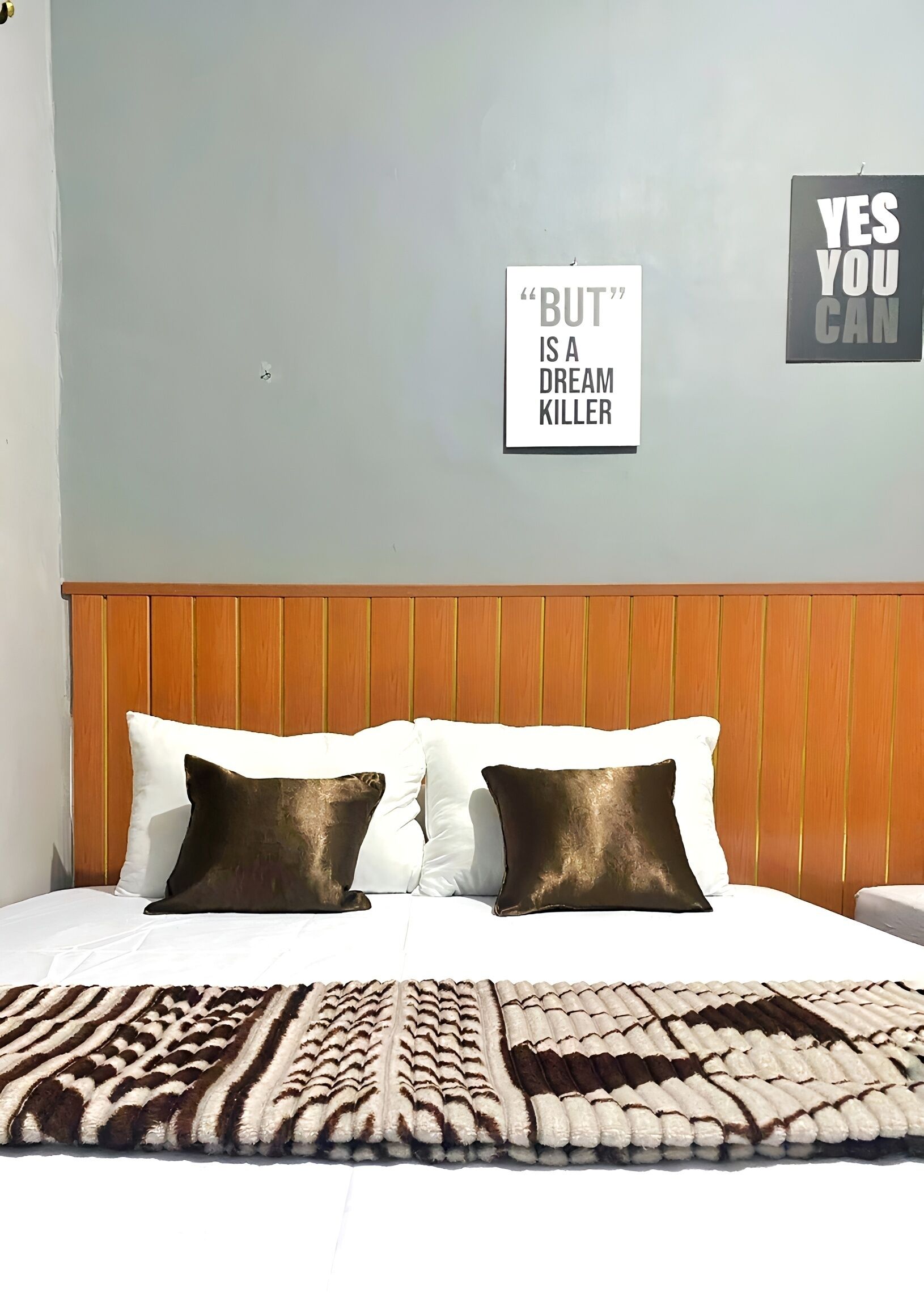 A bedroom with a wooden headboard, a patterned rug, and two pillows.