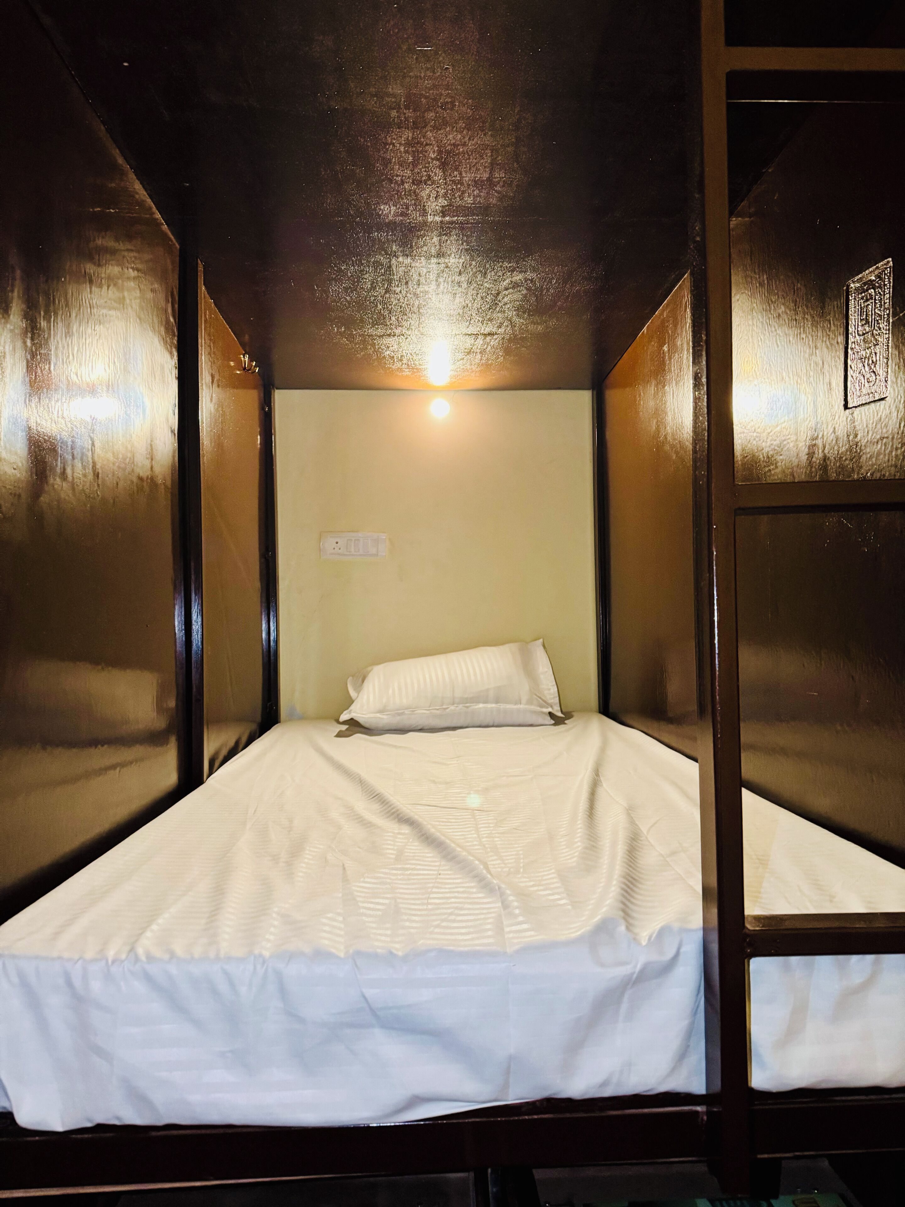 A single bed in a room with wooden walls and a ceiling light.