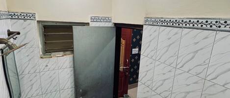 Une petite salle de bain avec un lavabo, des toilettes et une porte donnant sur une autre pièce.
