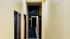 A narrow hallway with a checkered mat at the end, leading to a dark room. - Suraj Guest House (Varanasi)