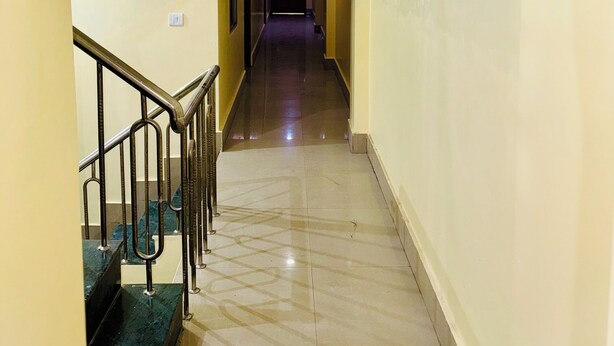 A hotel corridor with a marble staircase and a straight hallway leading to a darkened room. - Suraj Guest House (Varanasi)