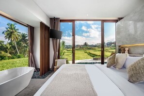 Ein Schlafzimmer mit einem großen Bett, einer Badewanne und einem Fernseher. Es bietet Blick auf eine grüne Landschaft und einen klaren Himmel.