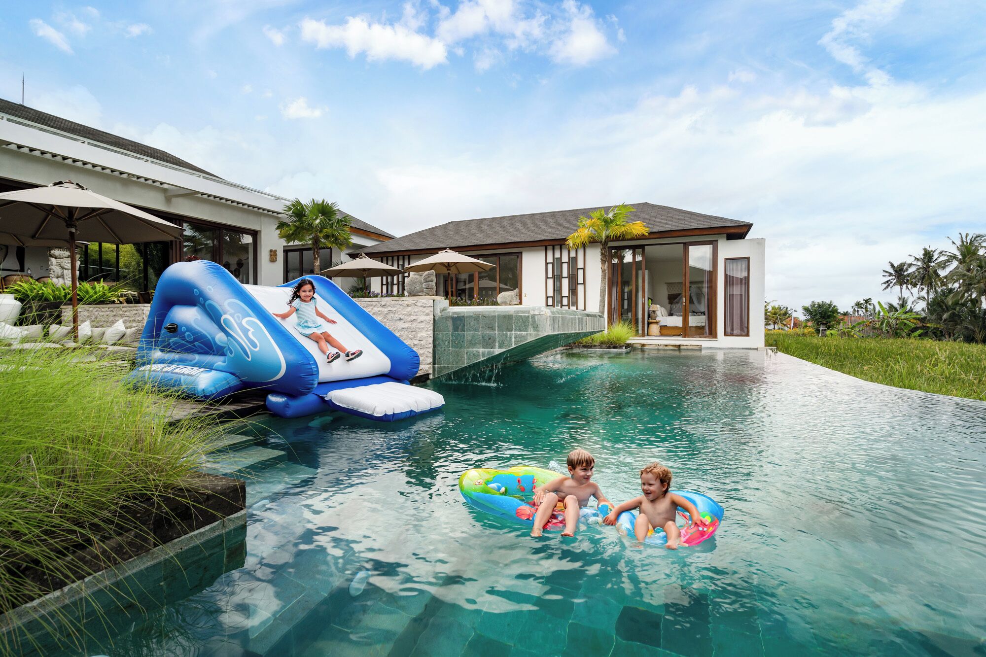 Piscina com toboáguas infláveis e duas crianças brincando.