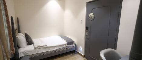 A bedroom with a bed, a desk, a chair, a door, and a ceiling fan.