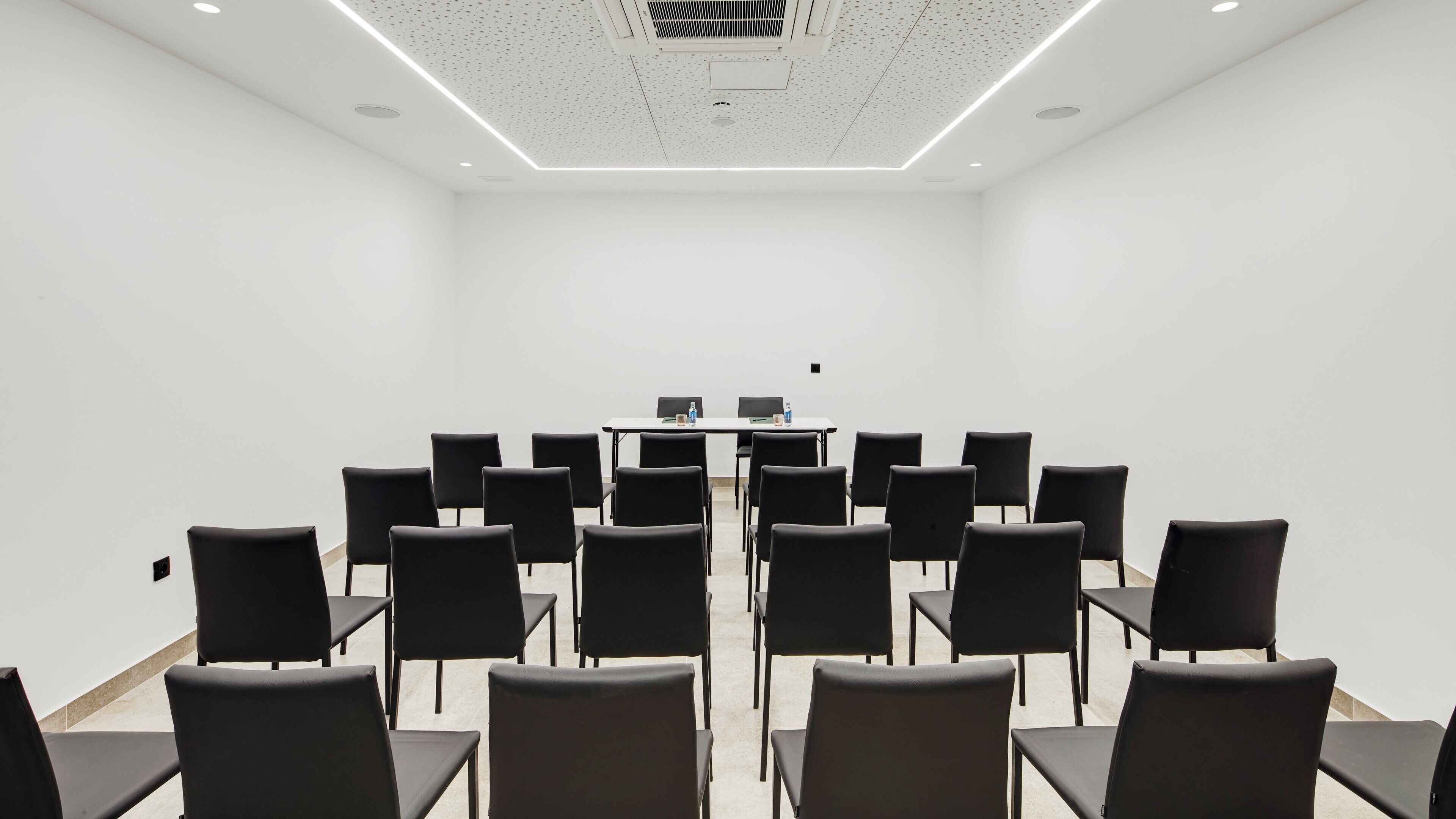 Une salle de conférence avec une longue table et des chaises disposées pour une réunion.