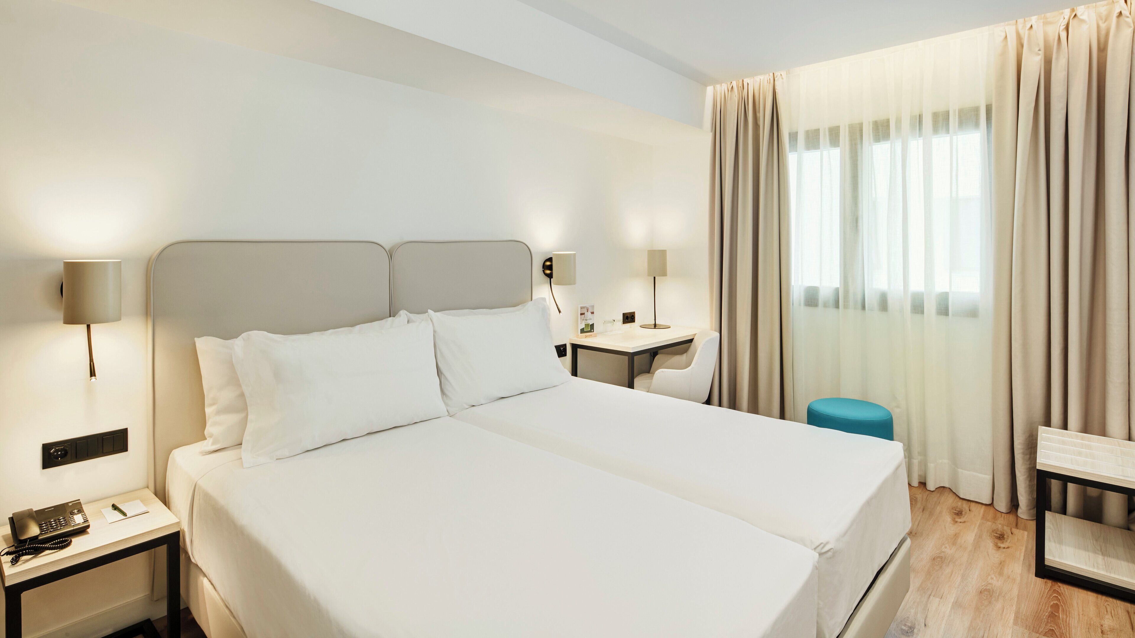 A hotel room with a large bed, bedside tables, a desk, and a chair.
