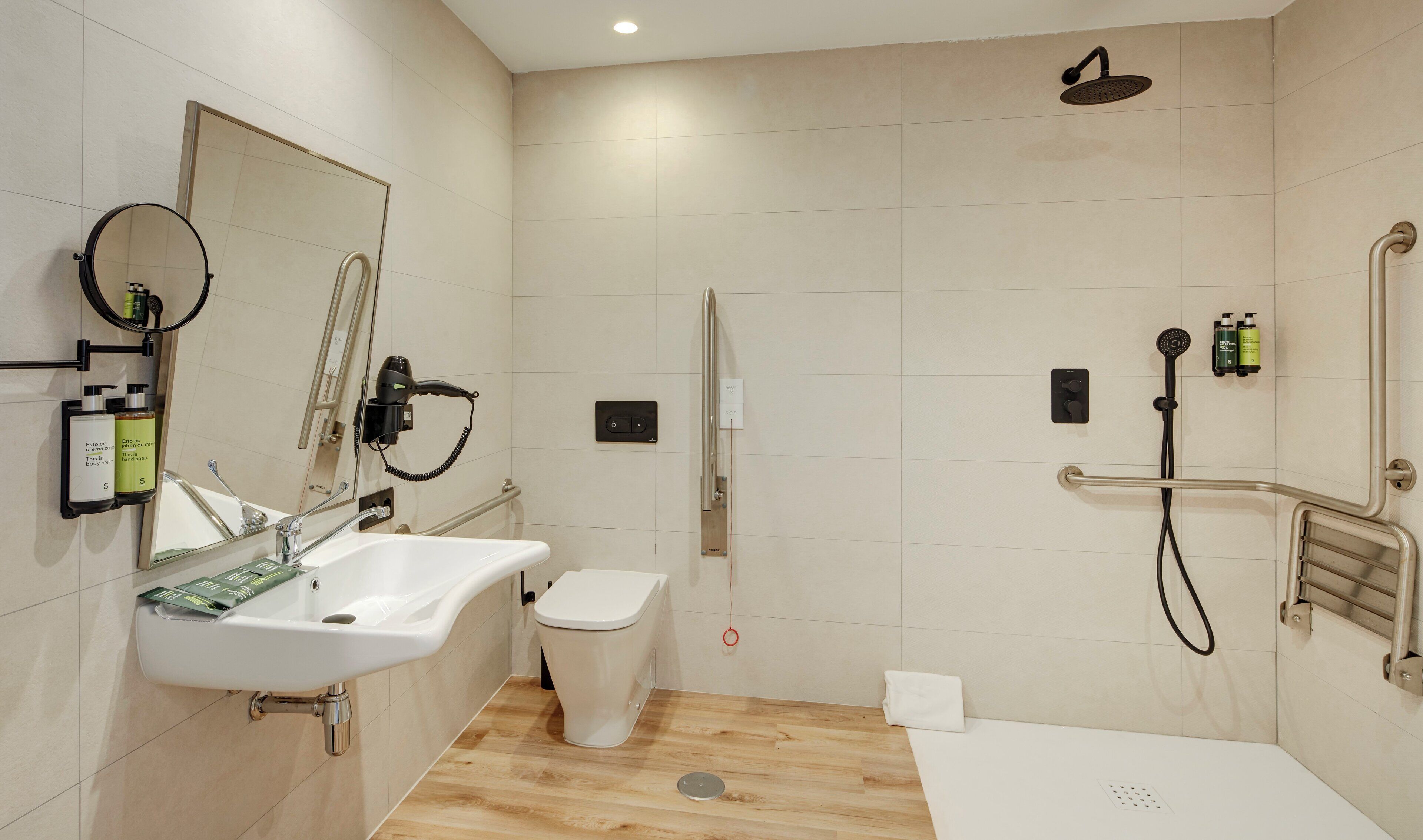 A modern bathroom with a sink, mirror, hairdryer, and shower.