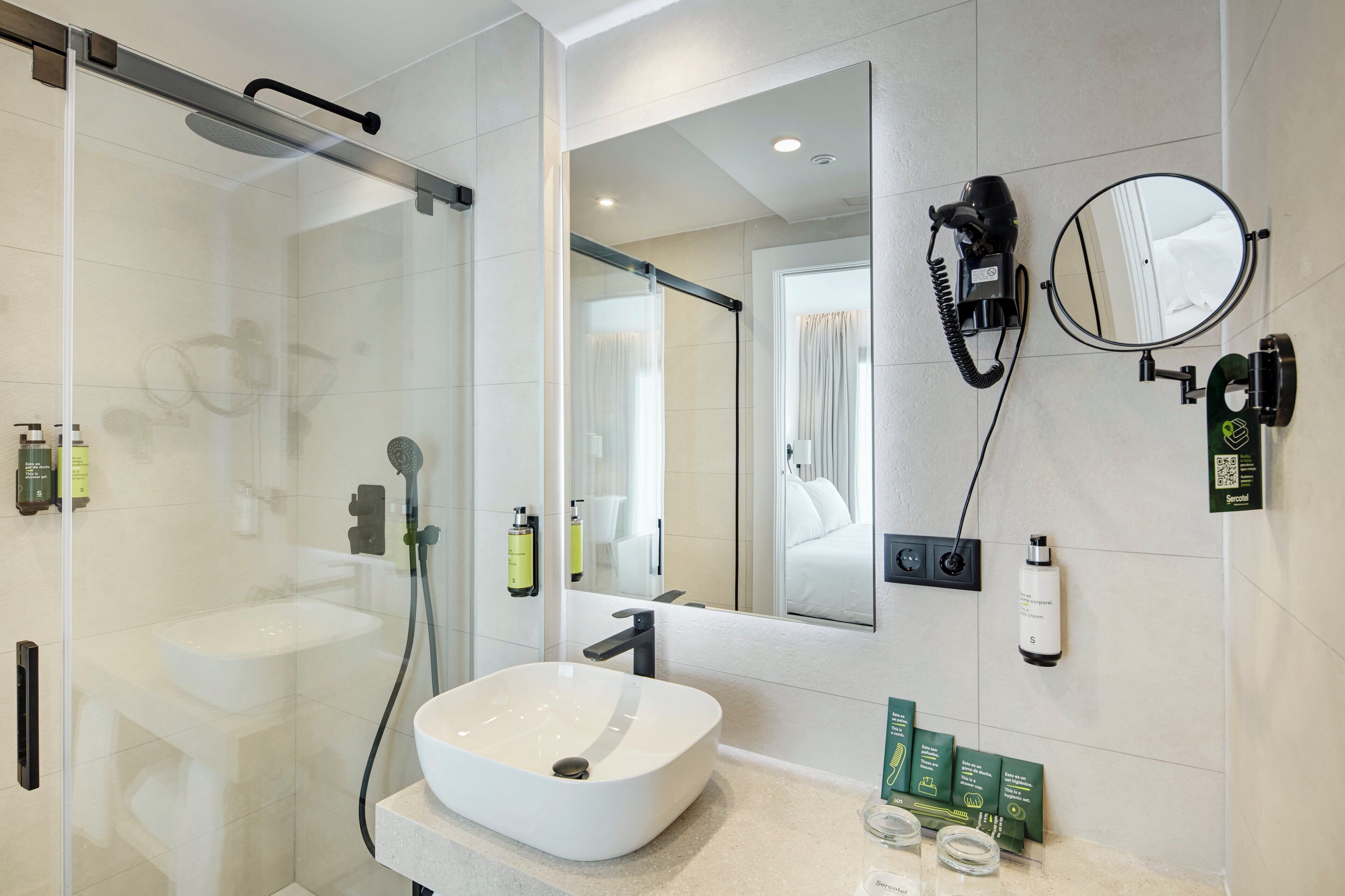 A modern bathroom with a glass-enclosed shower, a white sink, and a large mirror.