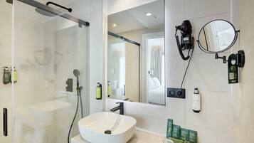 A modern bathroom with a glass-enclosed shower, a white sink, and a large mirror.