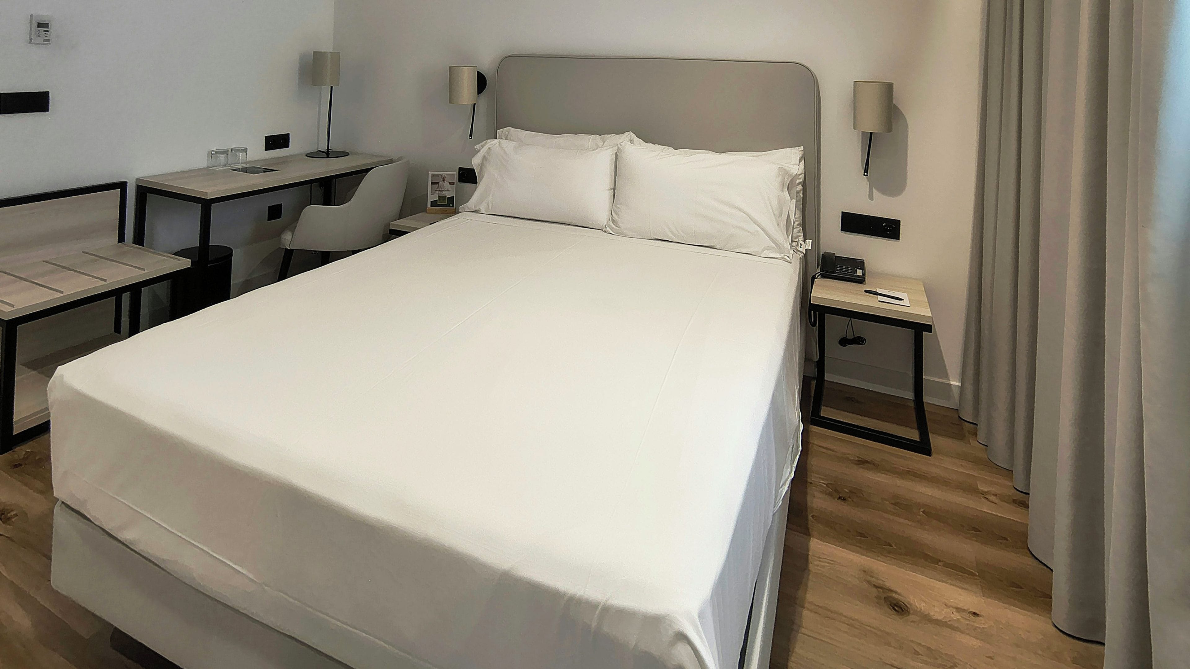 Ein Hotelzimmer mit einem großen Bett, einem Schreibtisch, einem Sessel, einem Nachttisch und einer Lampe.