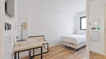 Un dormitorio moderno y minimalista con cama, una mesita pequeña y un escritorio.