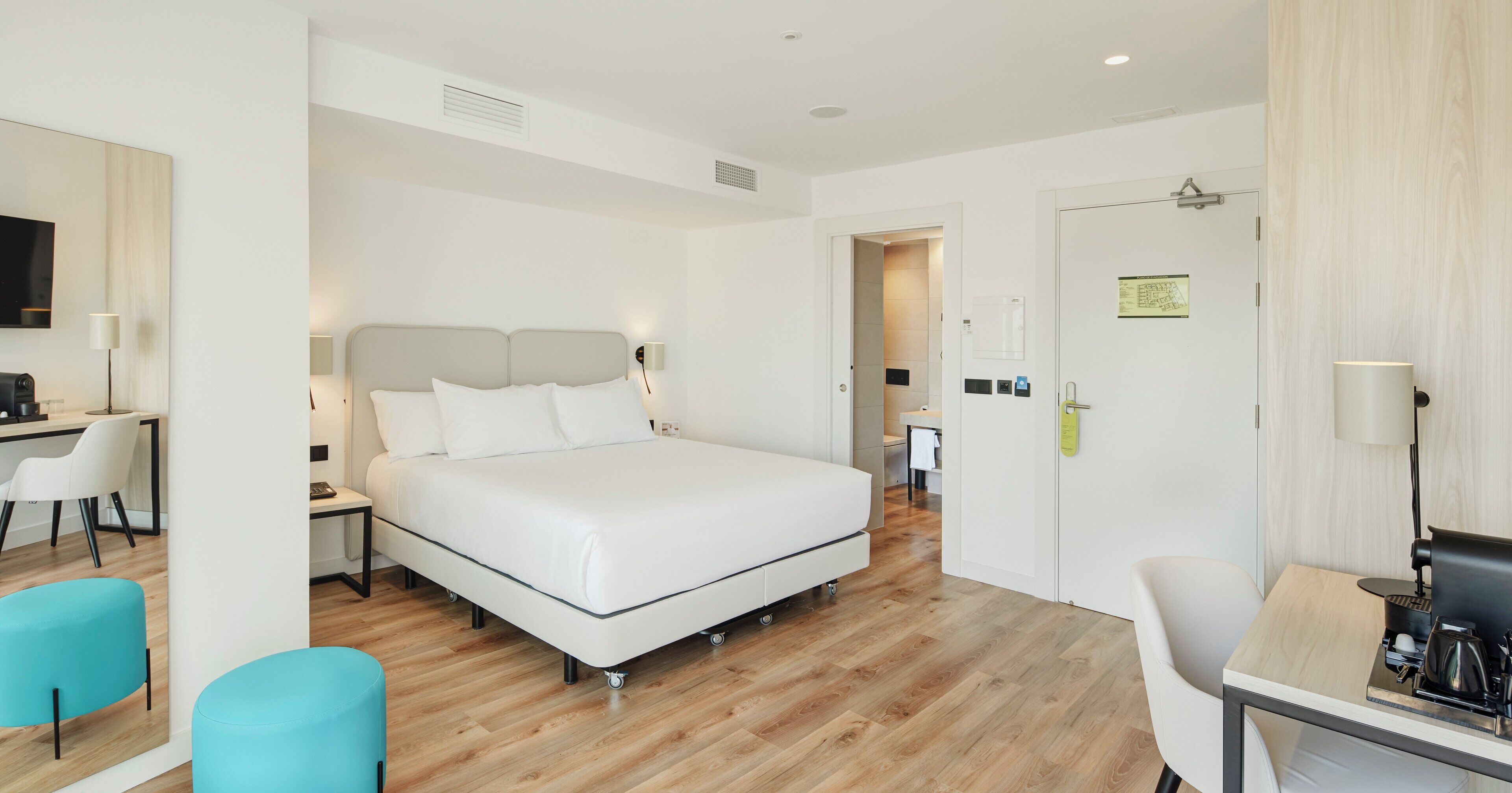 A modern hotel room with a bed, a desk, and a chair.