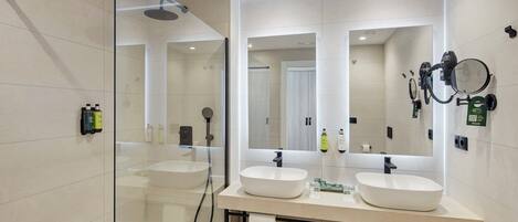 A modern bathroom with two sinks, a glass shower enclosure, and a large mirror.