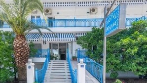 A hotel entrance with a staircase, blue railings, and a sign indicating hotel amenities. - DELLIS (Kamena Vourla)