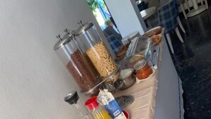 A breakfast buffet with various cereals, bread, and beverages. - DELLIS (Kamena Vourla)