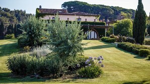 Una casa con jardín, una pérgola y un árbol alto.