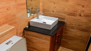 Un baño moderno con un inodoro blanco, un lavabo rectangular y paredes de madera.