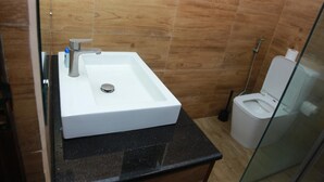 Un baño con lavamanos blanco, inodoro y cabina de ducha con mampara de vidrio.