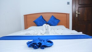 Una cama bien hecha con ropa de cama azul y blanca, un cabecero de madera y una toalla azul sobre la cama.