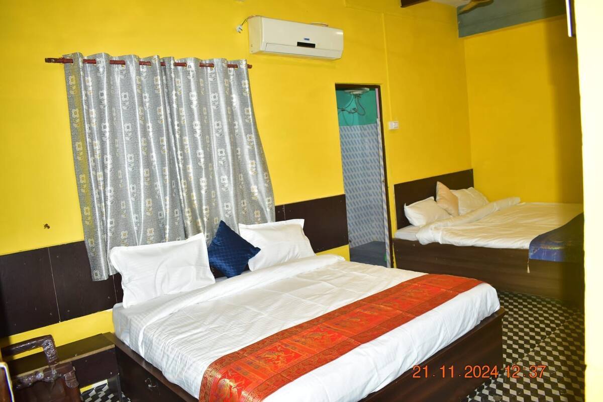 A hotel room with two beds, a window with curtains, a checkered floor, and a wall-mounted air conditioner.