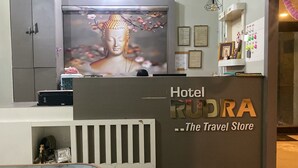 A reception desk at Hotel Rudra with a Buddha statue and cherry blossoms in the background. - Rudra Hotel (Varanasi)