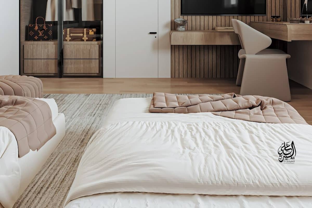 A modern bedroom with a large bed, a walk-in closet, a desk with a computer, and a TV.
