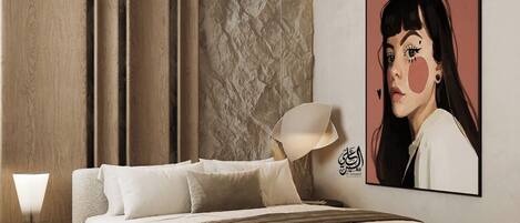A modern bedroom with a large bed, a nightstand, a lamp, and a wall-mounted artwork.