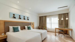 Een hotelkamer met twee bedden, een bureau, een stoel, een koffiekopje en een schilderij aan de muur.