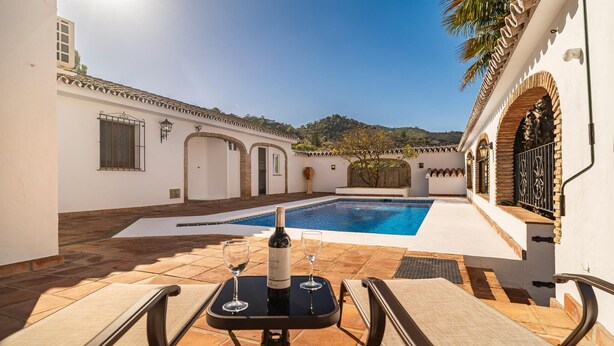 A poolside area with a table set for two, a bottle of wine, and a glass. - Awesome home in Guaro (Guaro)