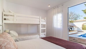 A bedroom with bunk beds, a large window with curtains, and a view of a swimming pool outside. - Awesome home in Guaro (Guaro)